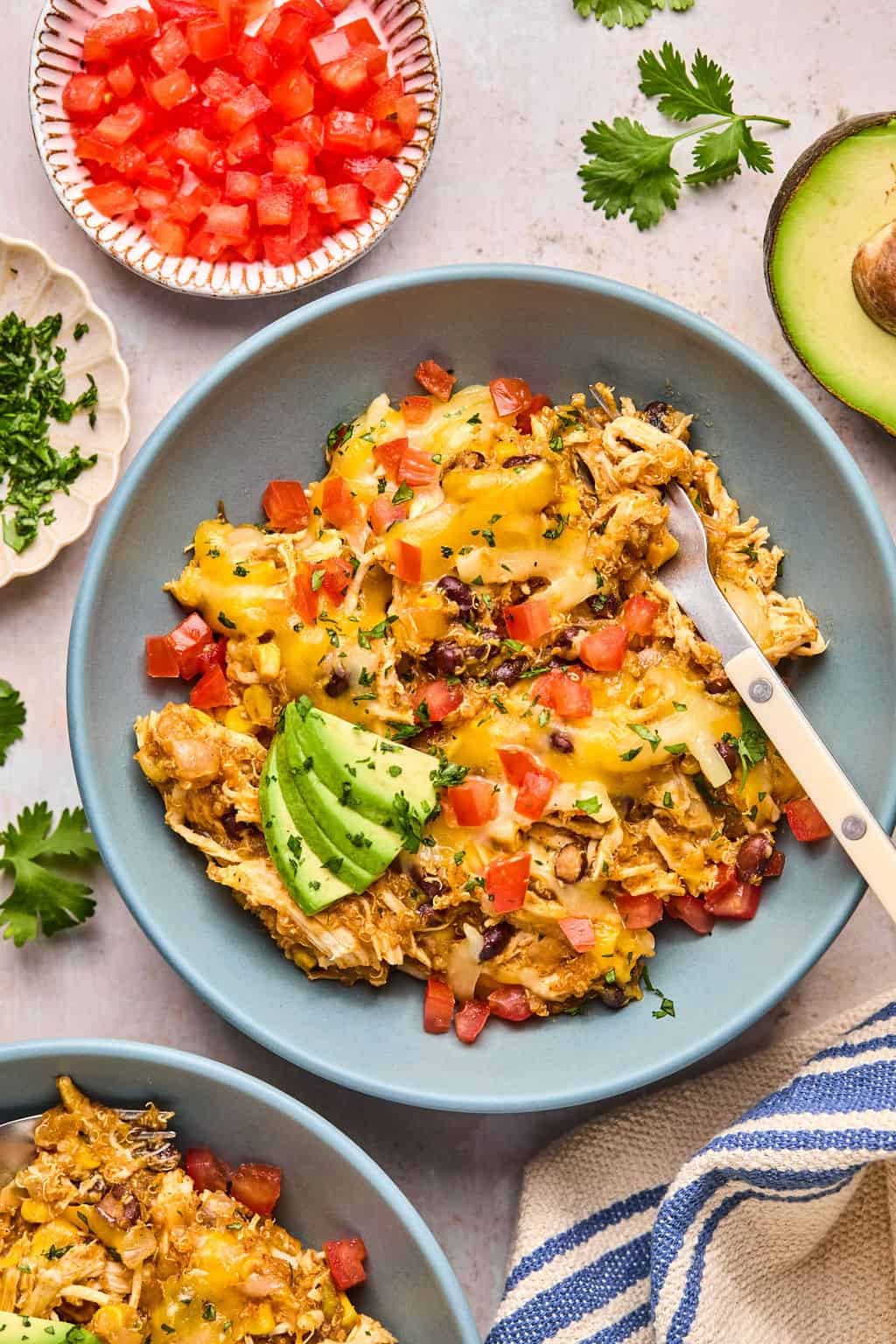 slow cooker taco casserole on a plate with cheese, tomatoes, and avocado.