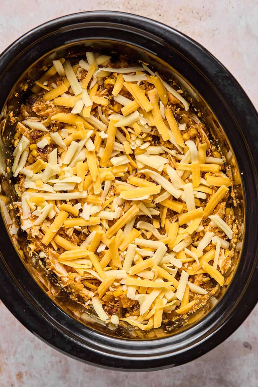 shredded cheese on top of mexican casserole in the crock pot.