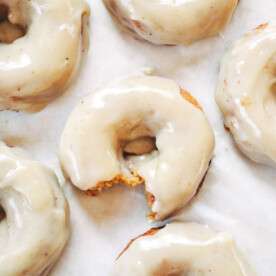 paleo pumpkin donuts on parchment paper with maple icing