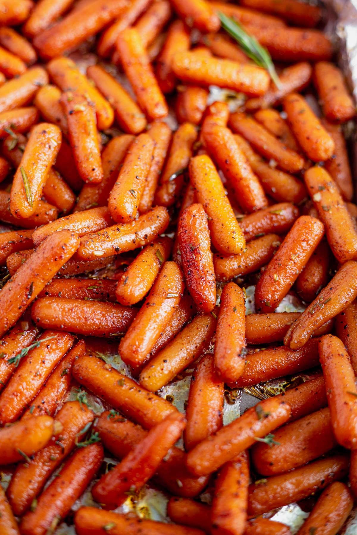 roasted maple carrots in a sweet and spicy sauce spread out on a baking pan