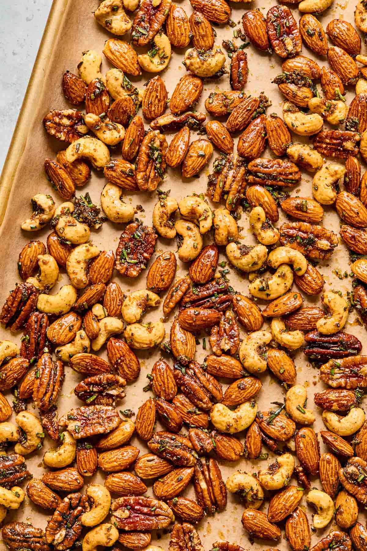 rosemary spiced nuts spread evenly on a baking sheet.
