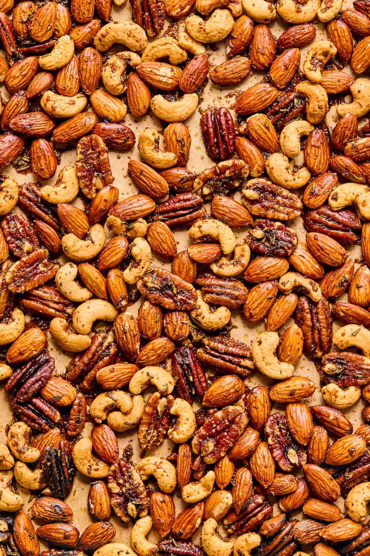 close up of roasted rosemary spiced nuts cooling on a baking sheet.