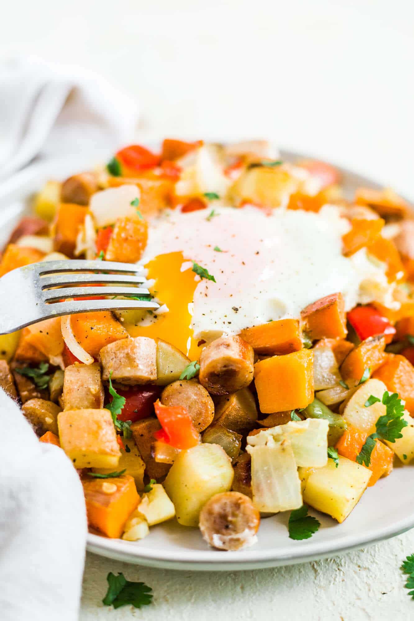 healthy sweet potato breakfast hash on a plate with an over easy egg