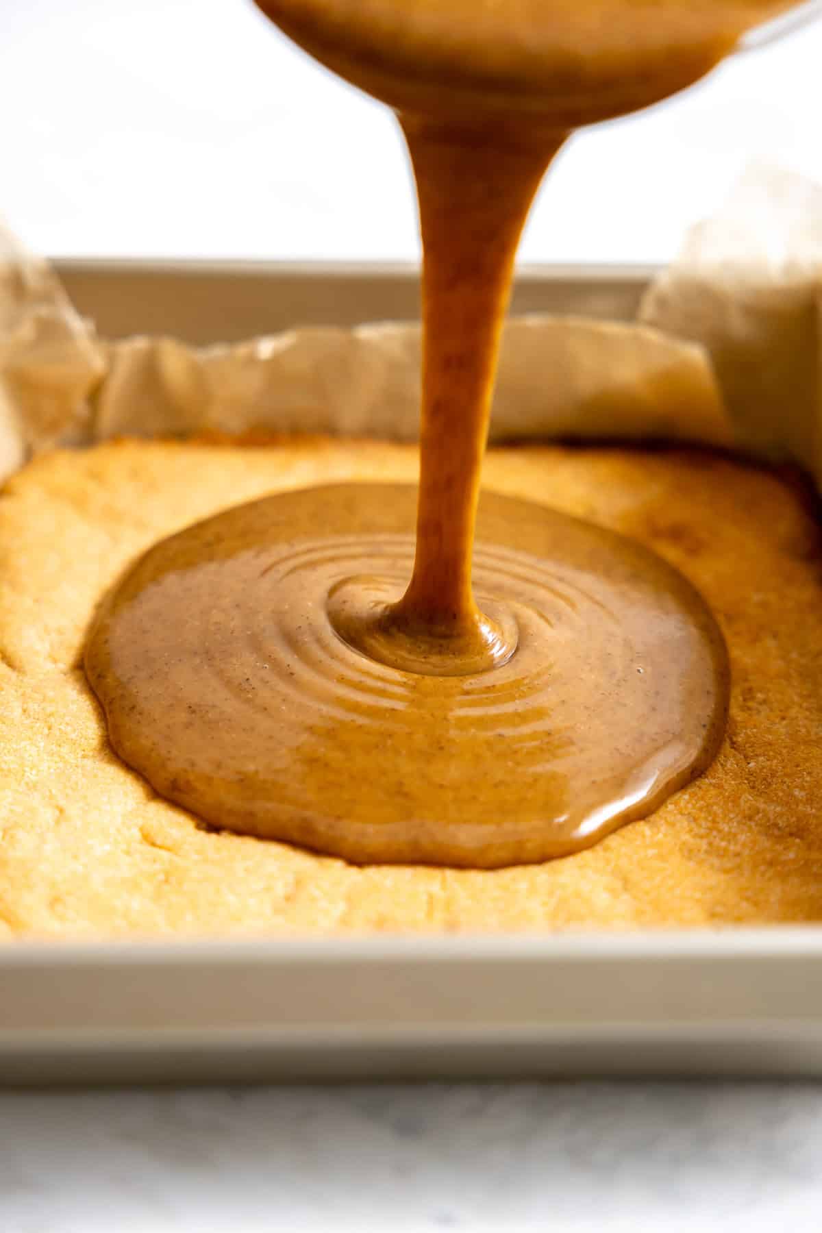 pouring healthy homemade caramel over baked shortbread.