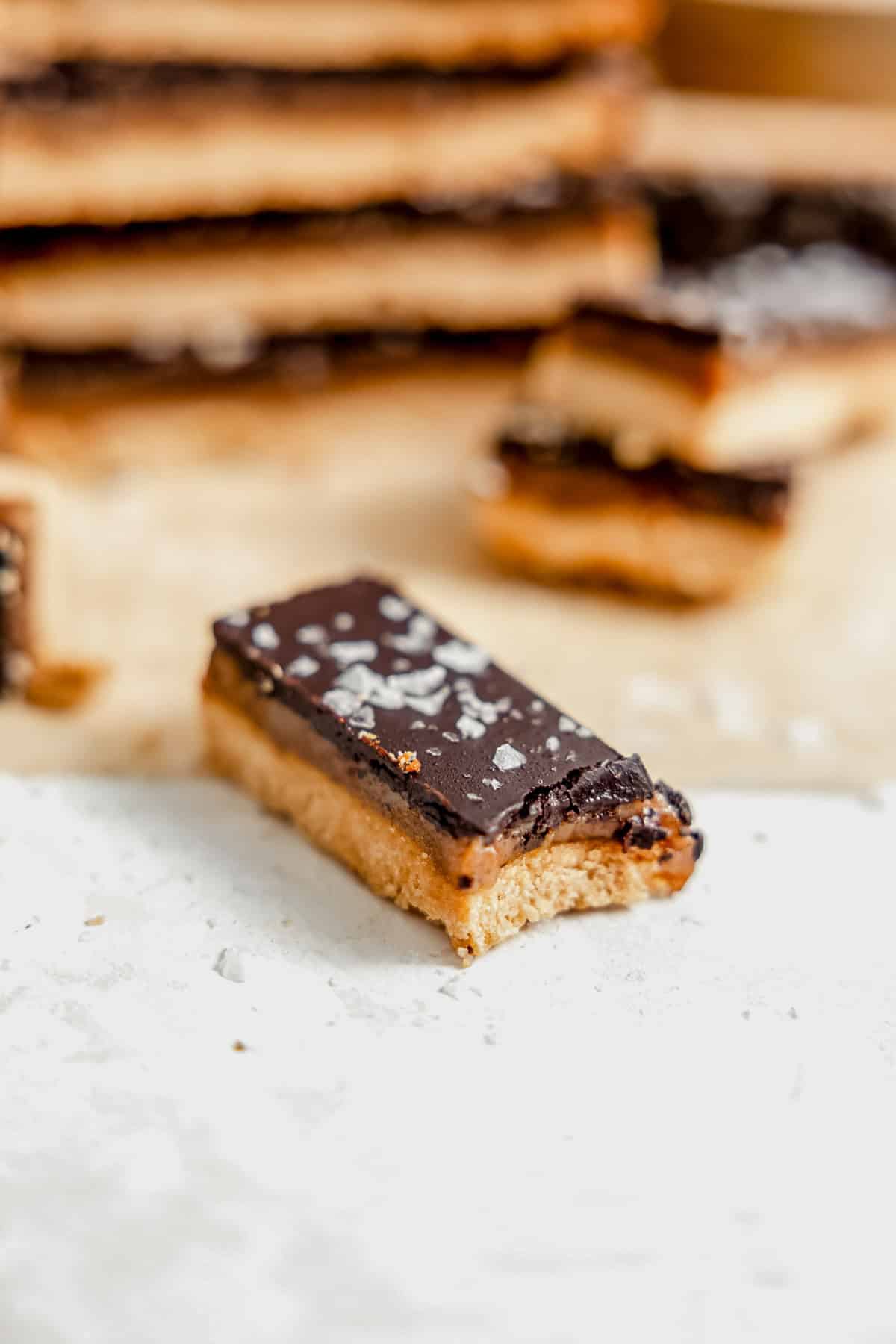 a bite taken out of a healthy twix bar on a piece of parchment paper.