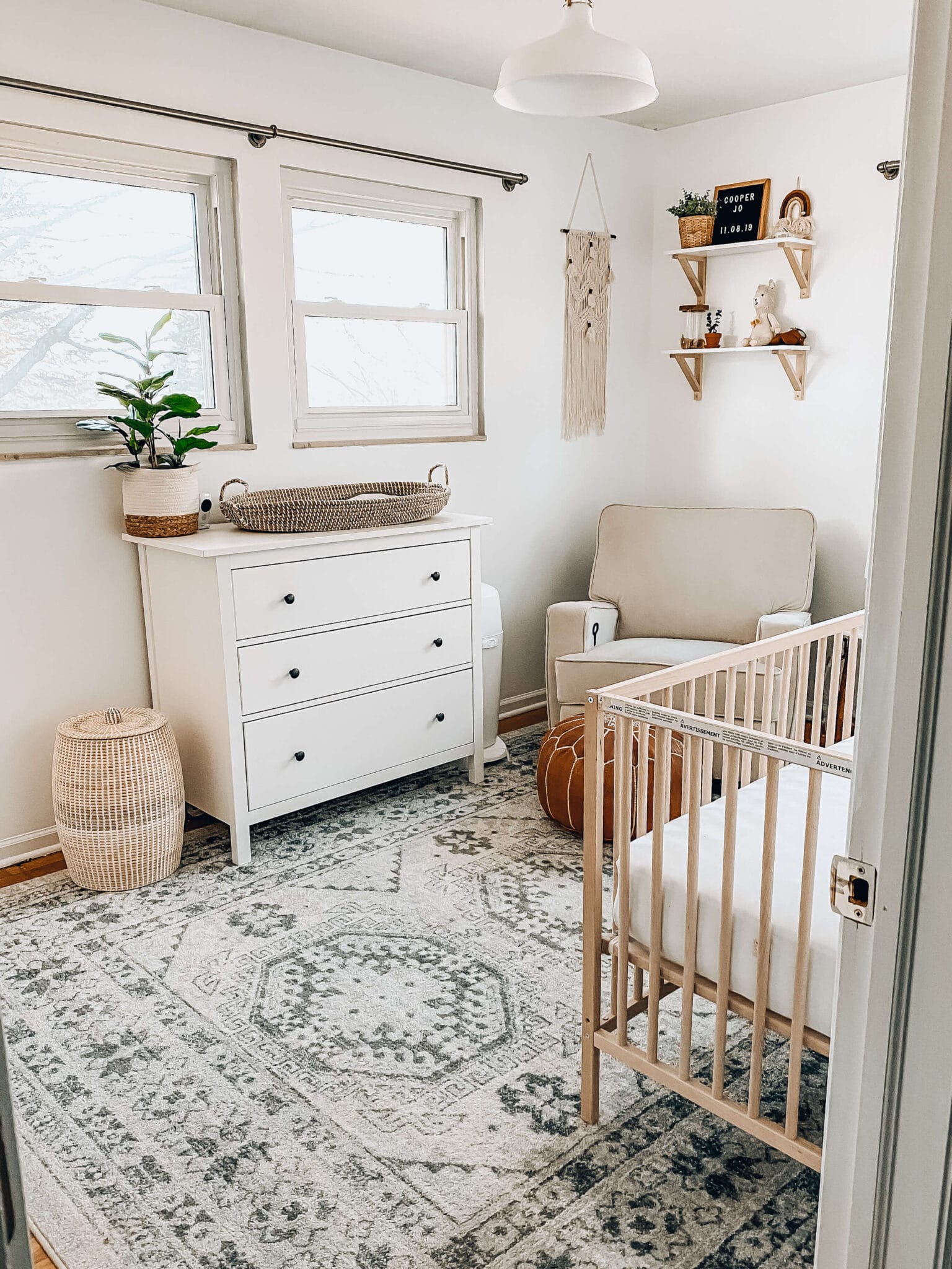 picture of neutral boho nursery with natural wood crib, white dresser, boho rug, and boho accents