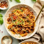 a bowl of gluten free spaghetti and meat sauce with fresh basil on top.