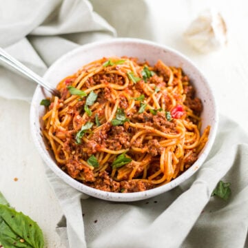 instant pot spaghetti in a white bowl with fresh basil
