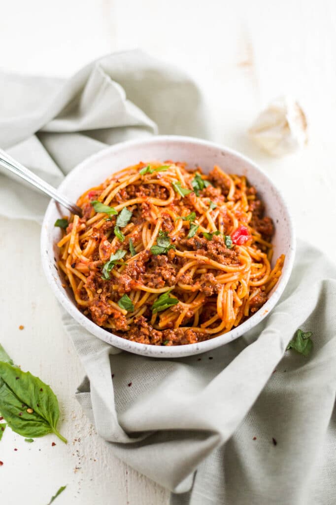 instant pot spaghetti in a white bowl with fresh basil 