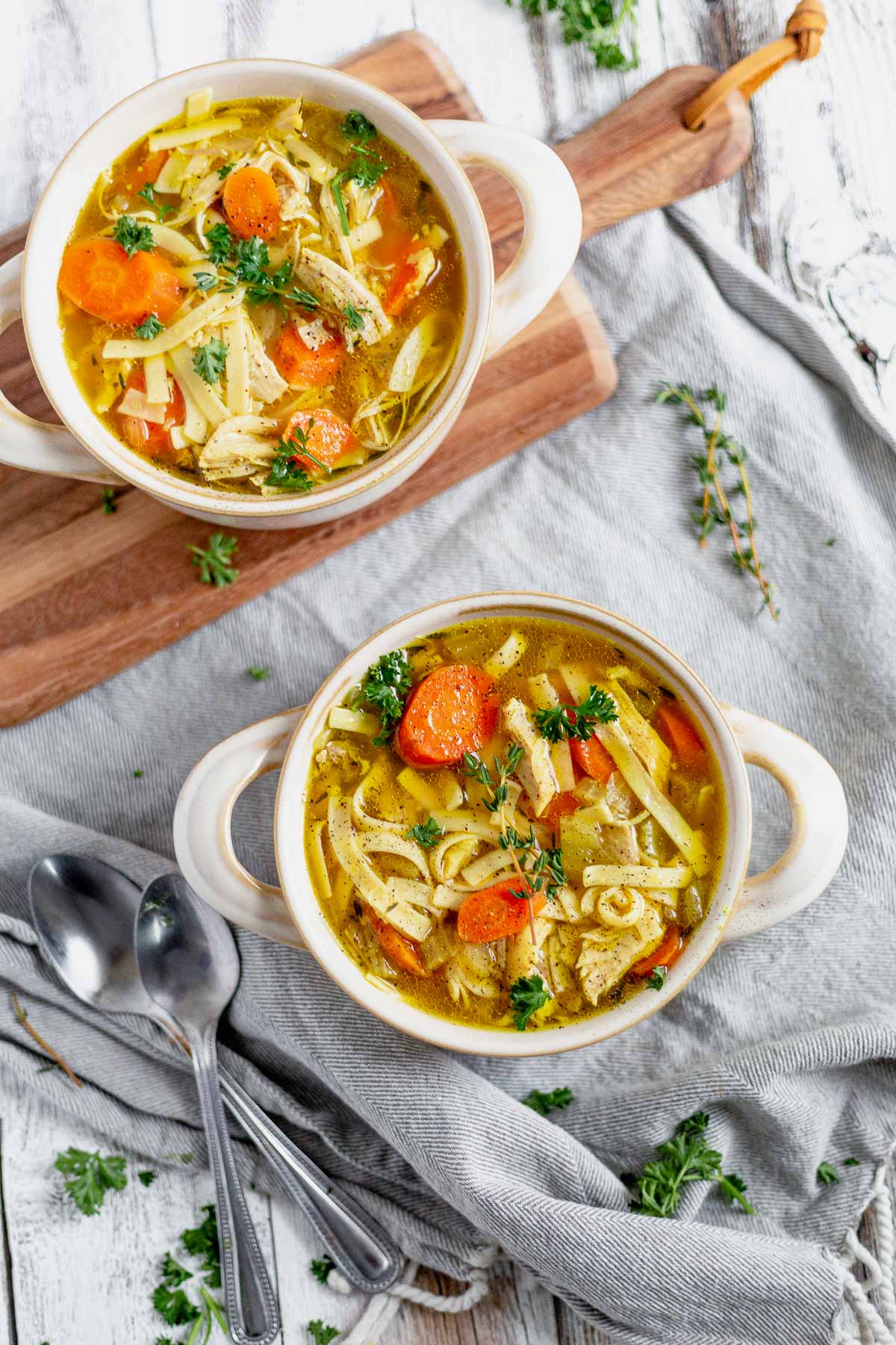 chicken noodle soup on a wooden board with fresh parsley around it