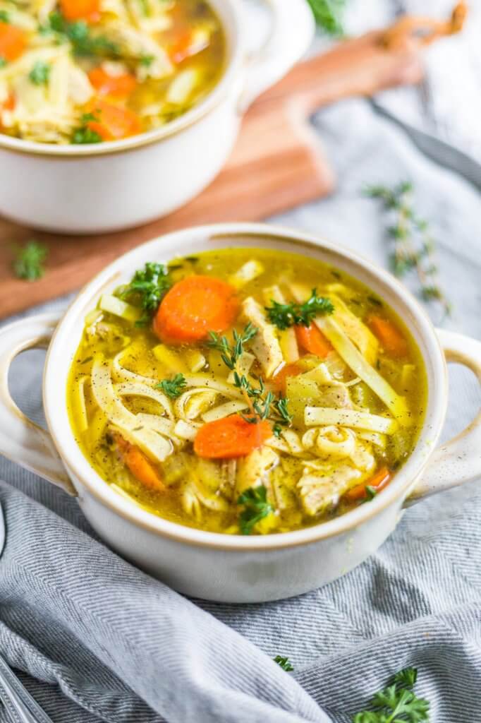 instant pot chicken noodle soup in a white bowl on a gray napkin