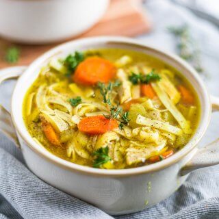a bowl of instant pot chicken noodle soup recipe with fresh thyme and parsley on top