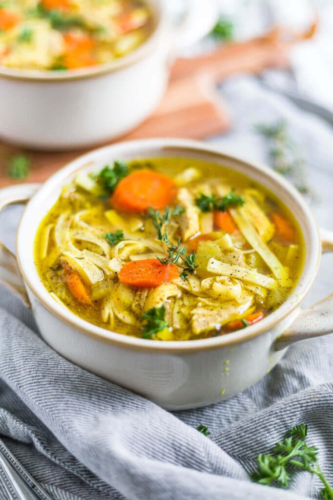 a bowl of instant pot chicken noodle soup recipe with fresh thyme and parsley on top