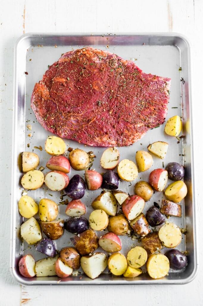 steak and potatoes on sheet pan before cooking in the oven
