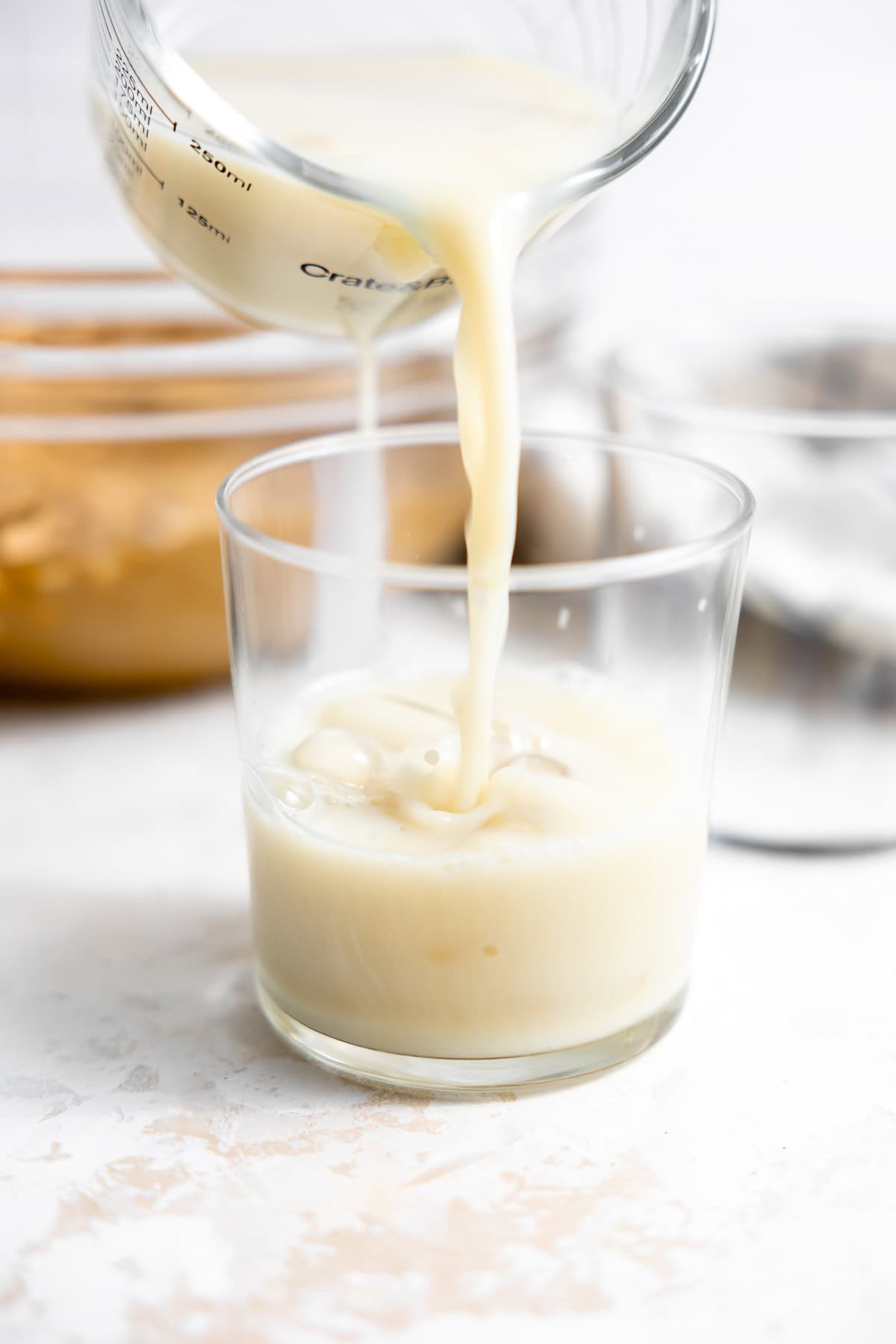 pouring oat milk into a glass of ice.