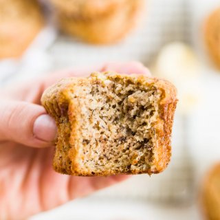 person holding a healthy banana muffin with a bite taken out