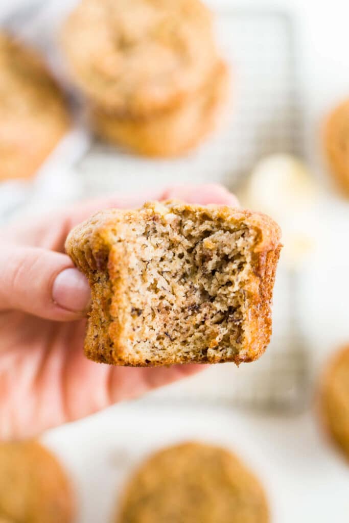 person holding a healthy banana muffin with a bite taken out