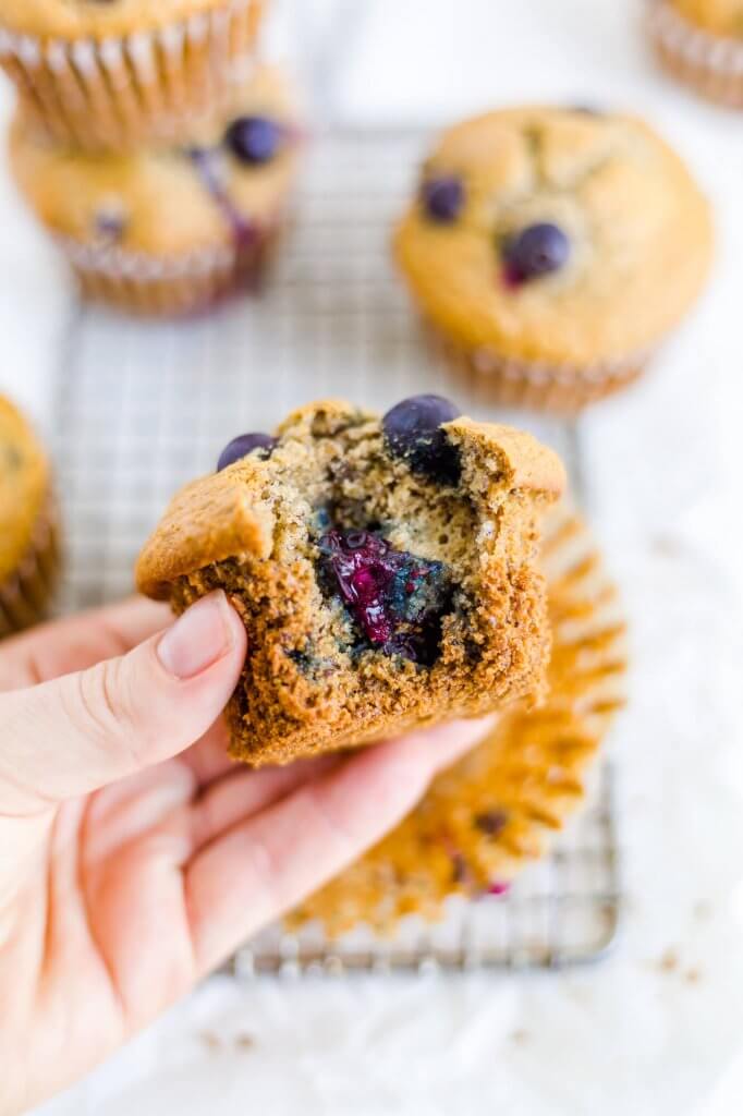 Hand holding a blueberry muffin with a bite taken out