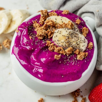 thick and creamy dragonfruit pitaya bowl topped with banana, granola and chia seeds