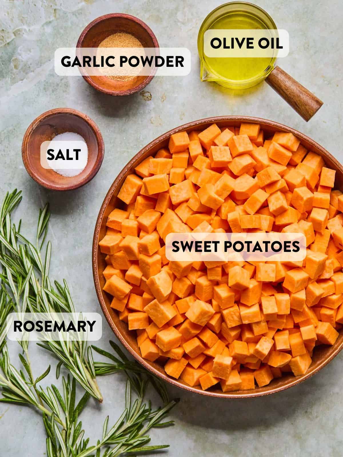 ingredients for rosemary sweet potatoes laid out in containers and bowls on a counter