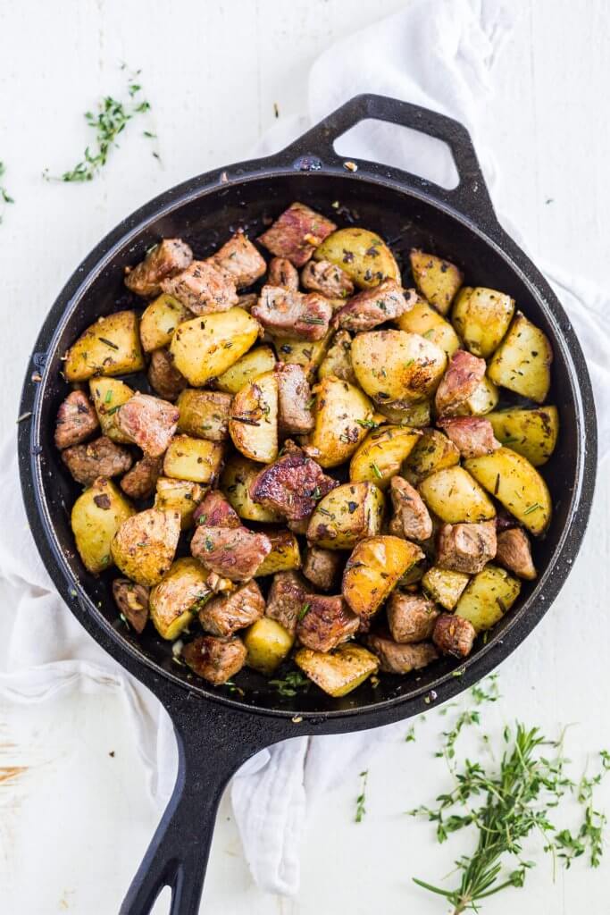 steak bites and potatoes in a cast iron skillet