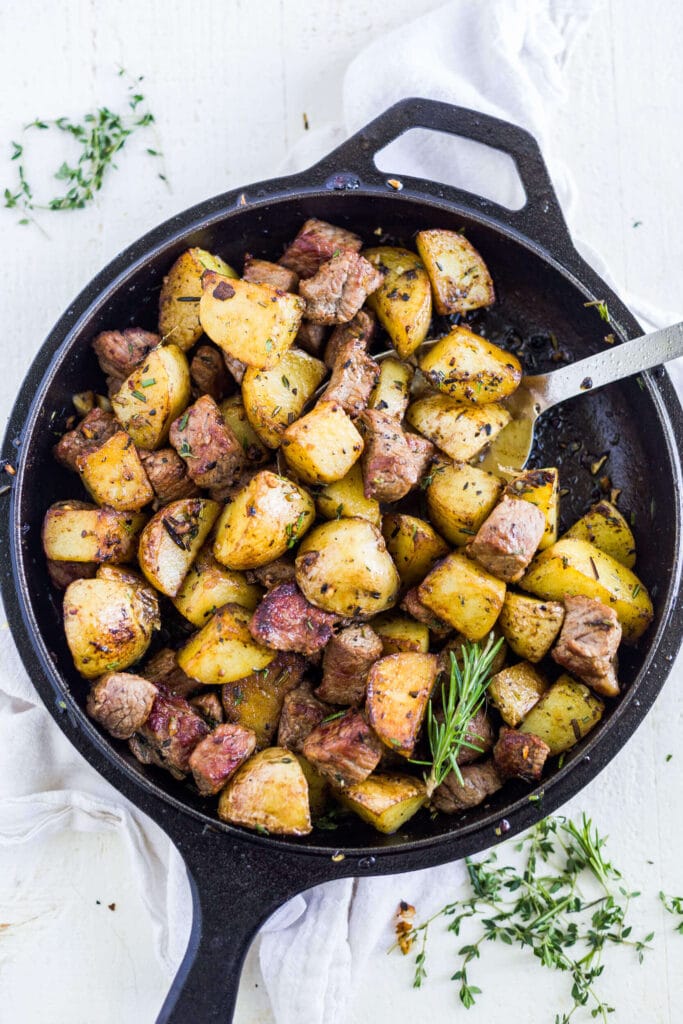 steak bites in a cast iron skillet with a spoon