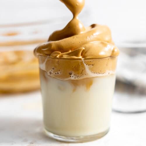 spooning whipped coffee over a glass of milk.