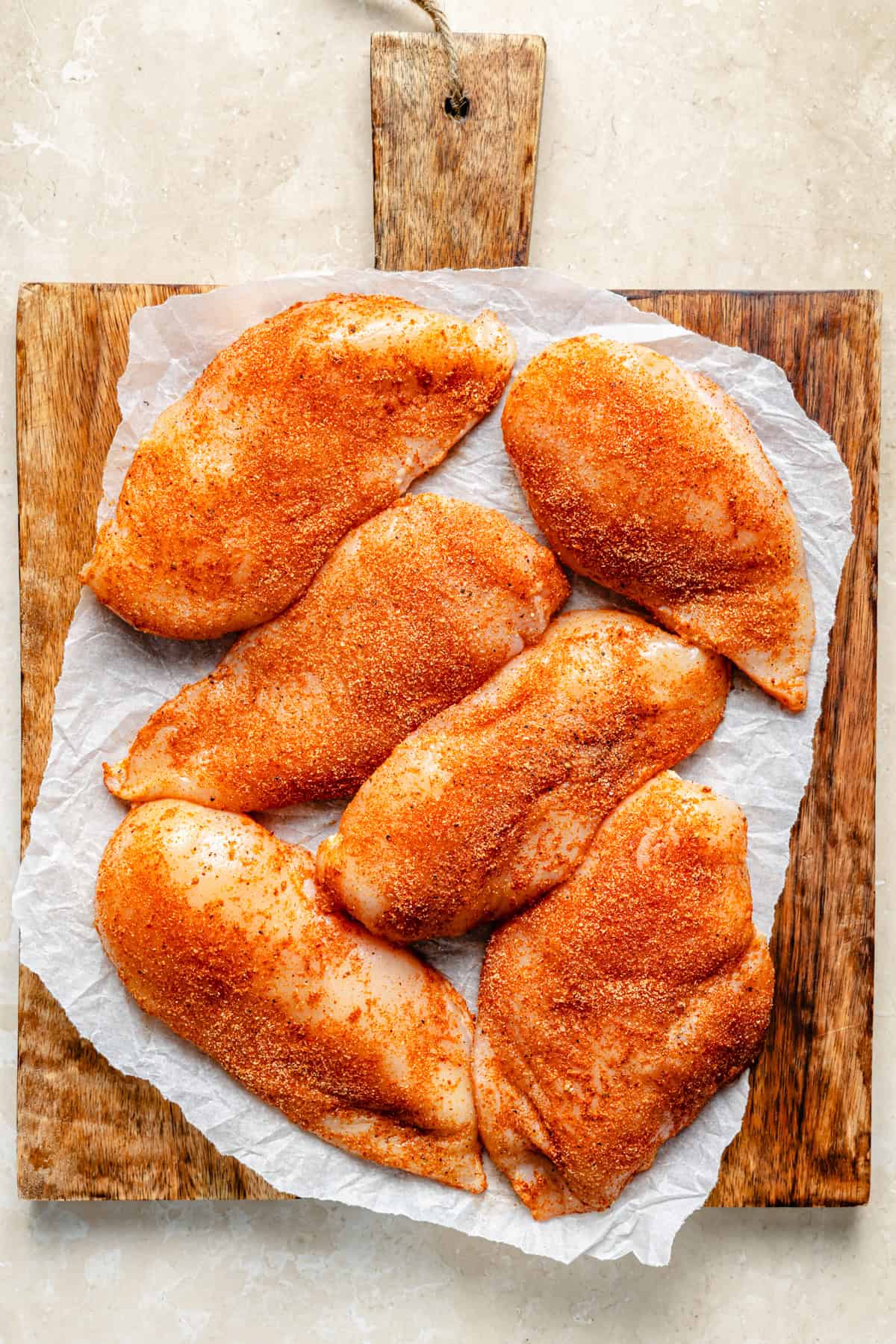 chicken breasts seasoned with dry rub on a cutting board.