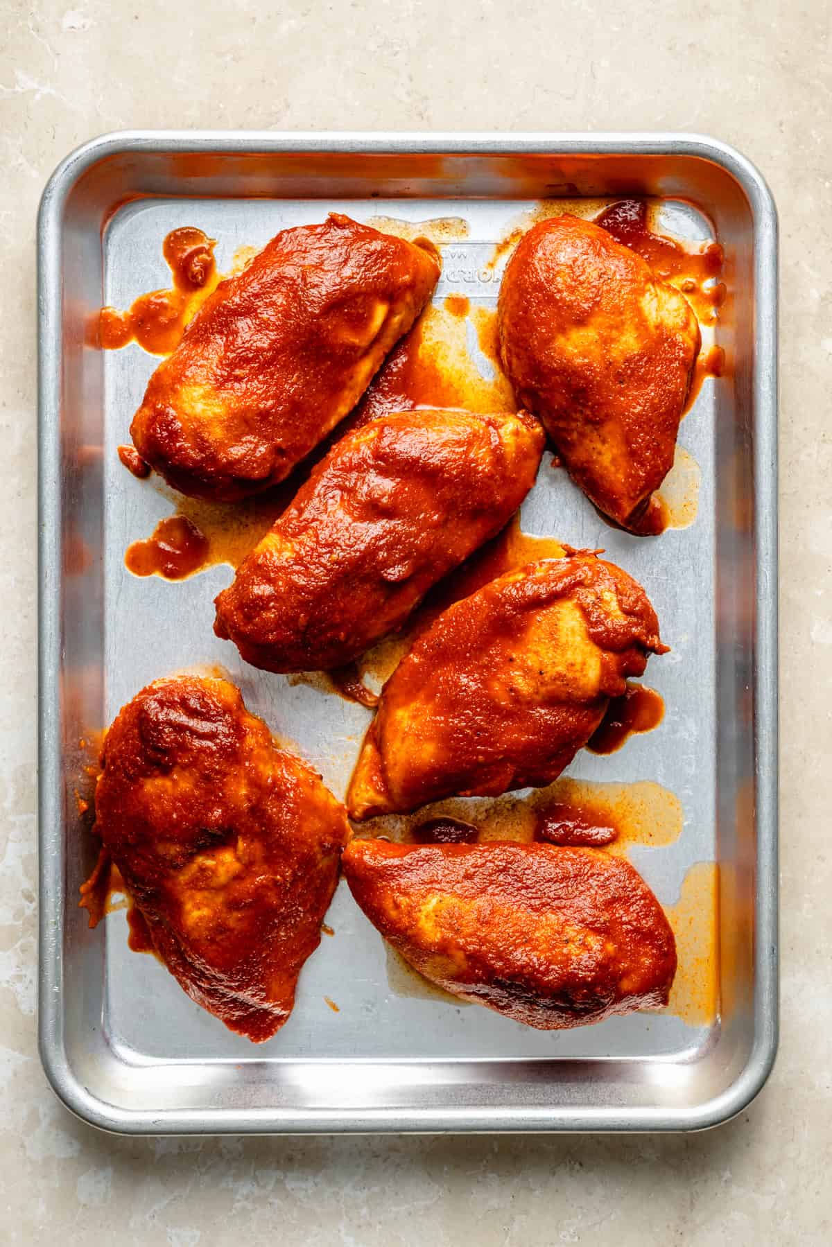 slow cooker cooker bbq chicken breasts on a sheet pan.