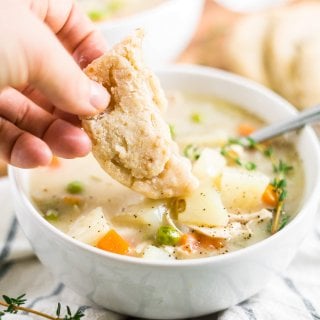 gluten free biscuit dunks into healthy chicken pot pie soup in a white bowl