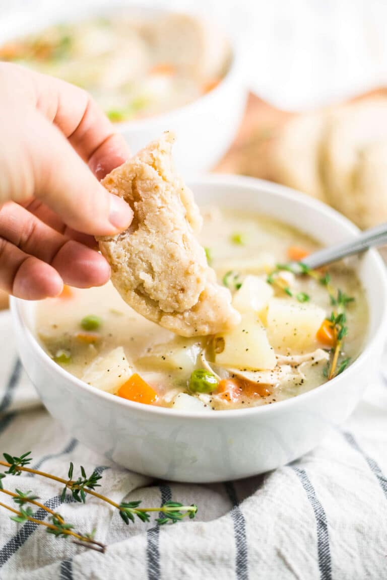 gluten free biscuit dunks into healthy chicken pot pie soup in a white bowl