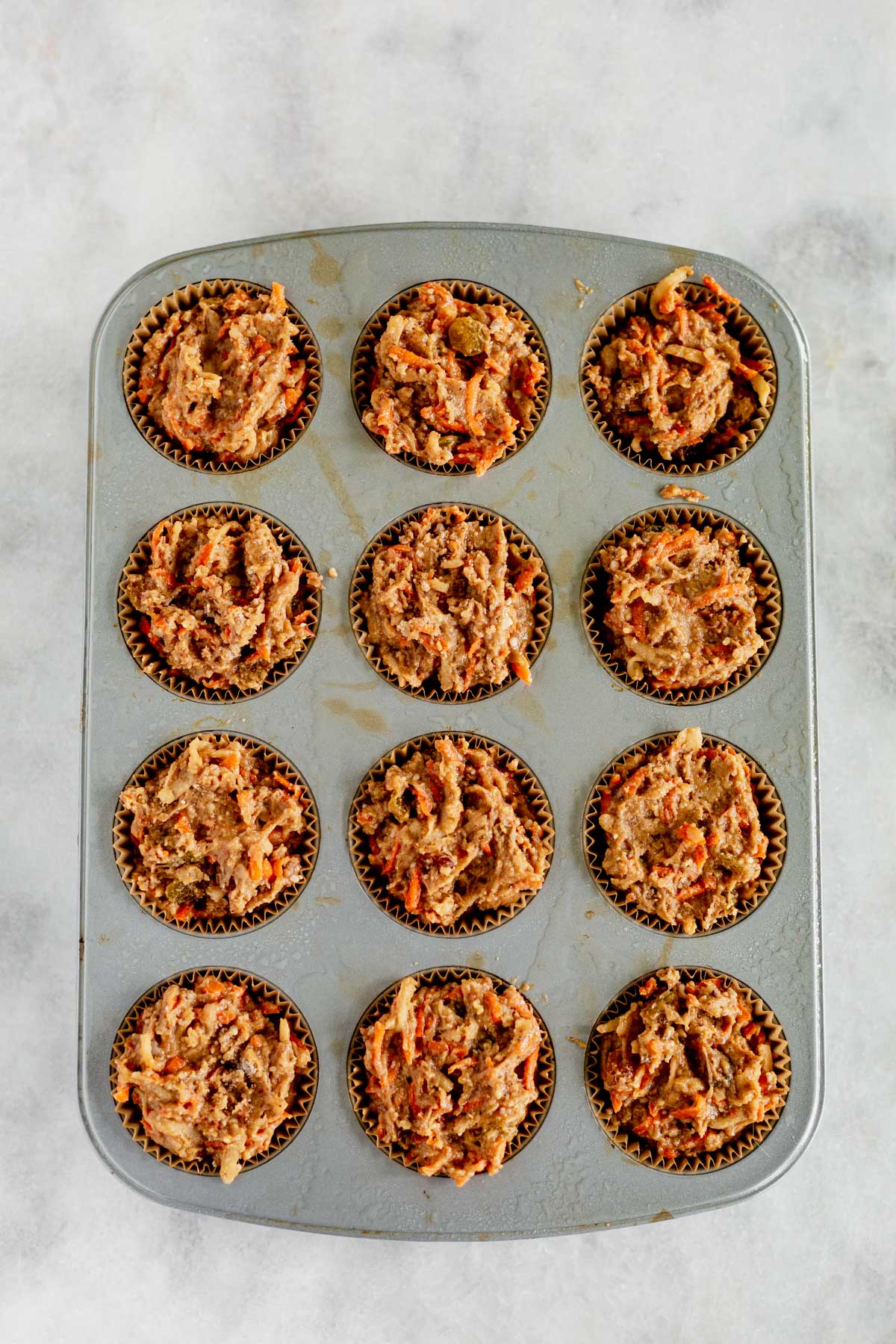 muffin tin filled with gluten free morning glory muffin batter