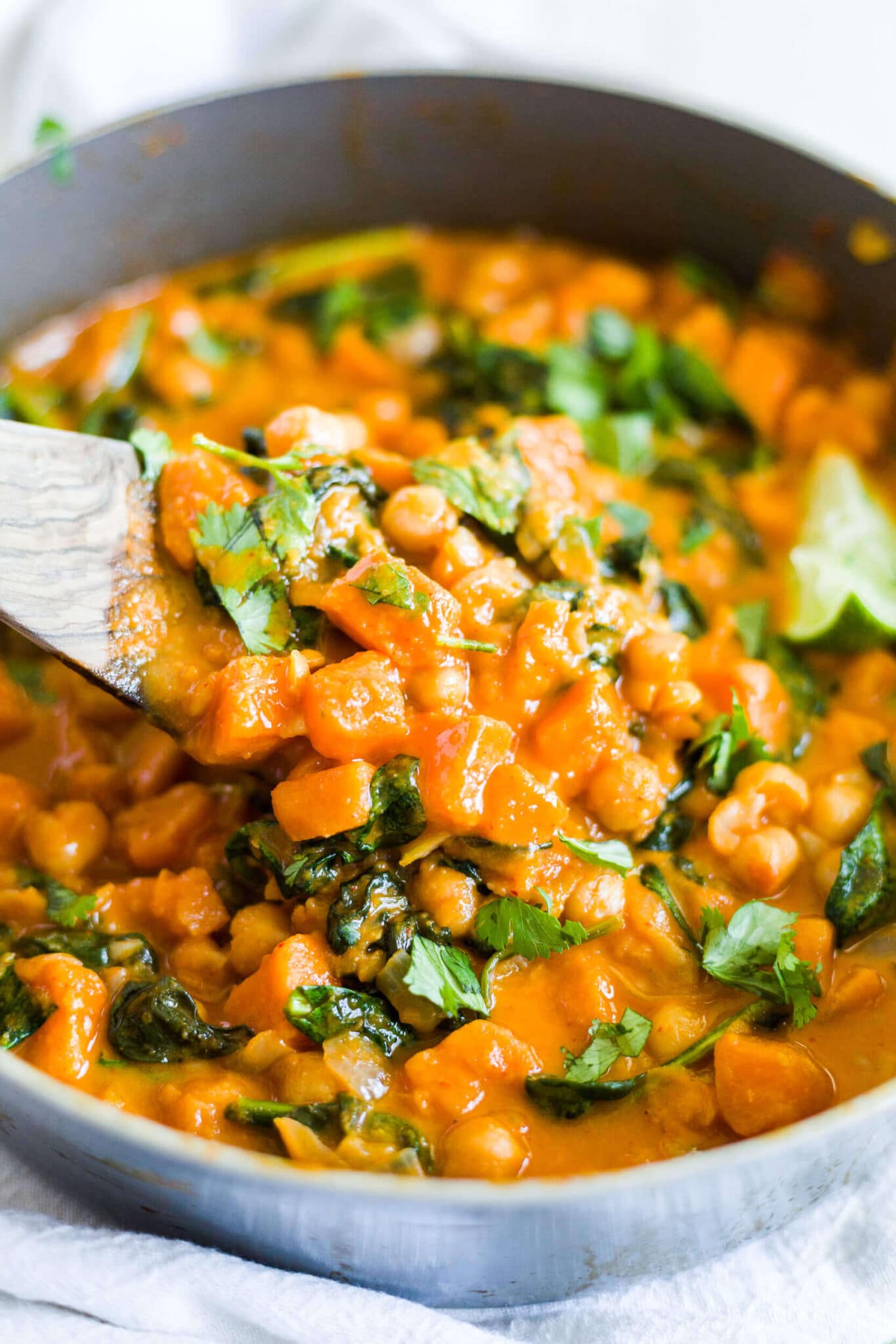 wooden spoon scooping out sweet potato curry from the pot