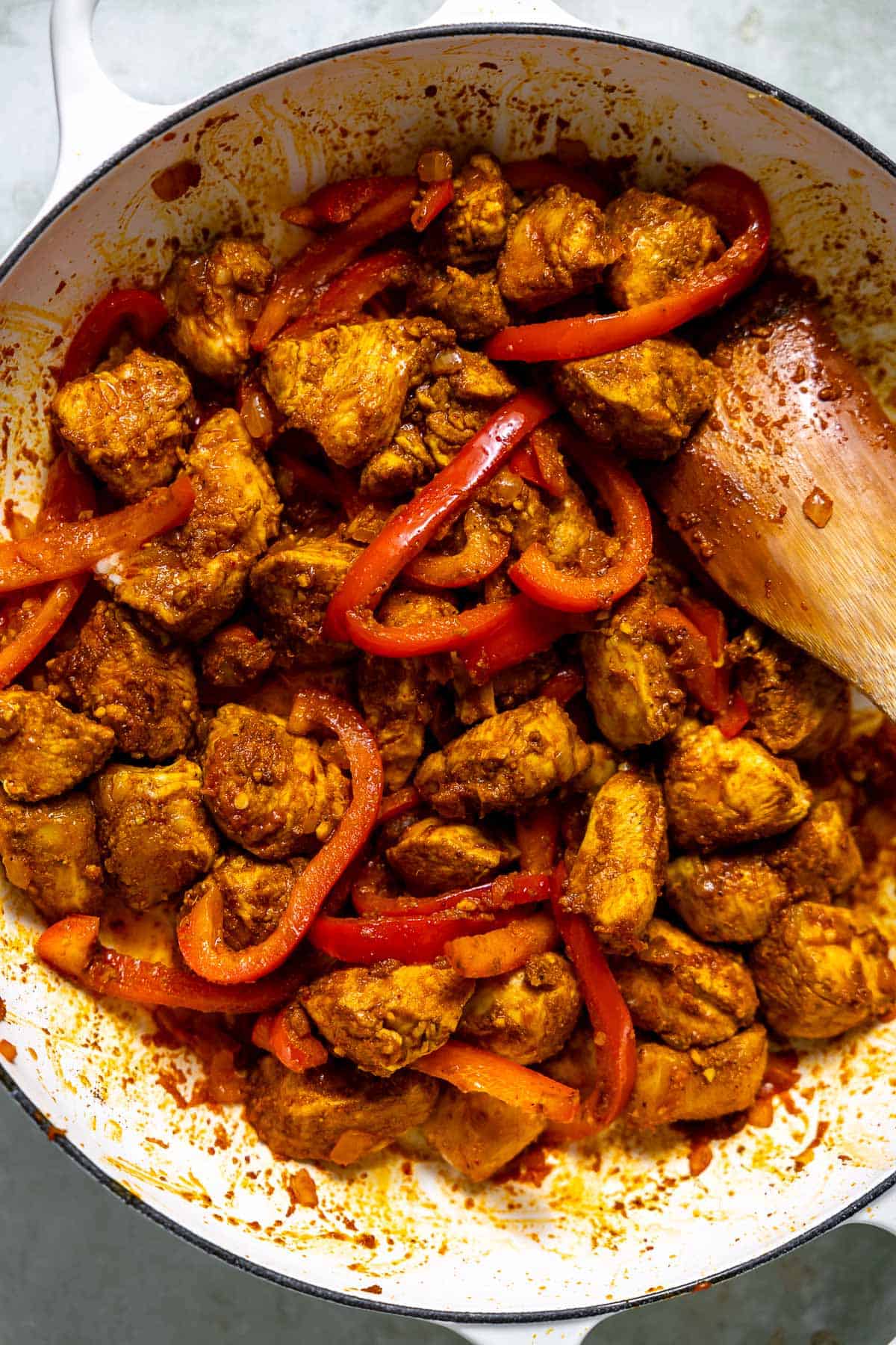 cooked diced chicken and red peppers in a skillet.