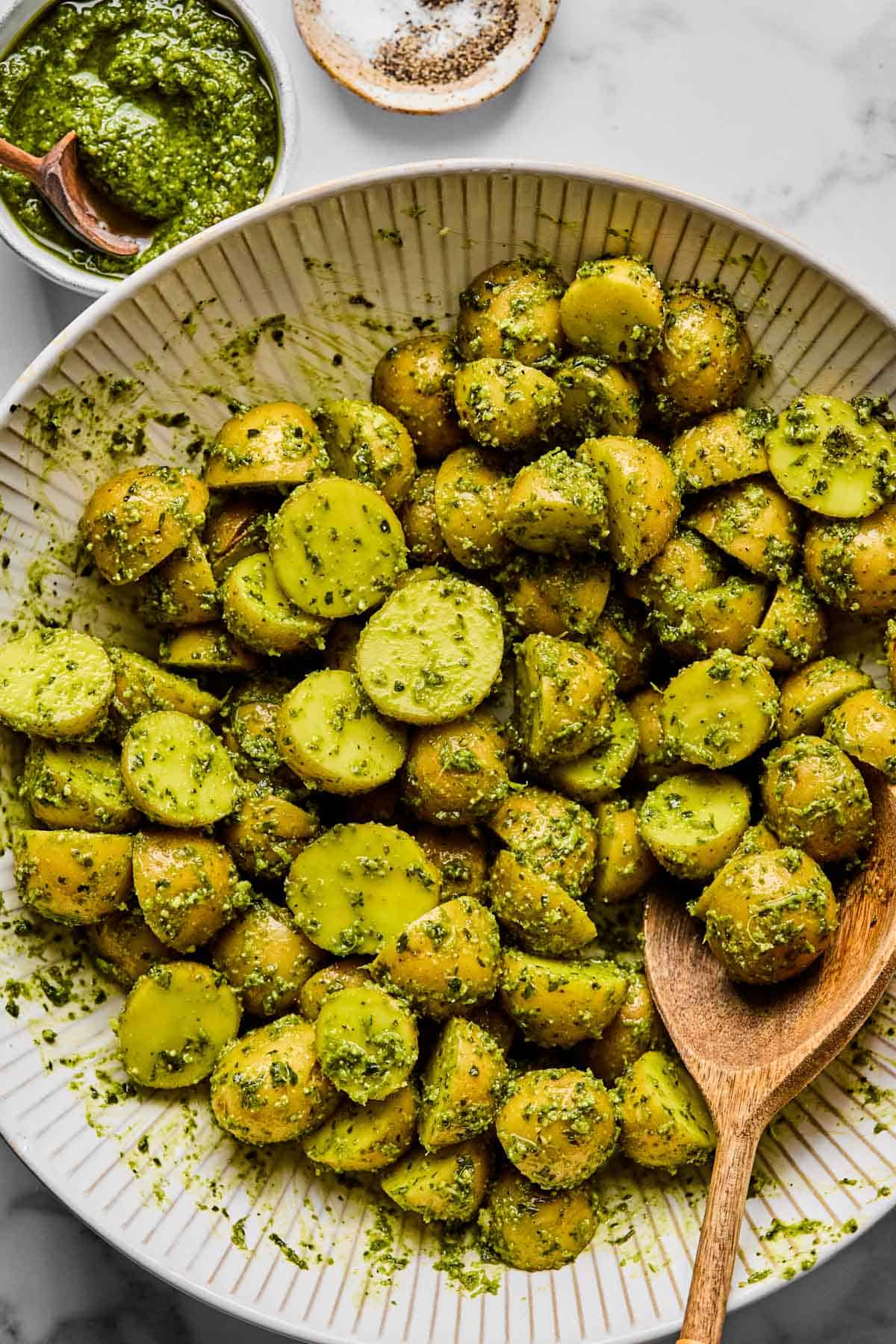 mini golden potatoes tossed in a bowl with pesto.