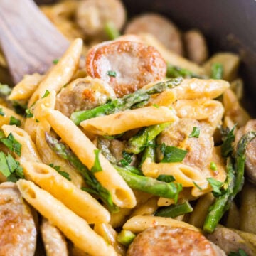 a wooden spoon scooping out chicken asparagus pasta