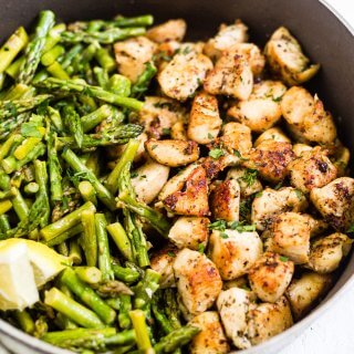 crispy chicken bites in a pan with asparagus
