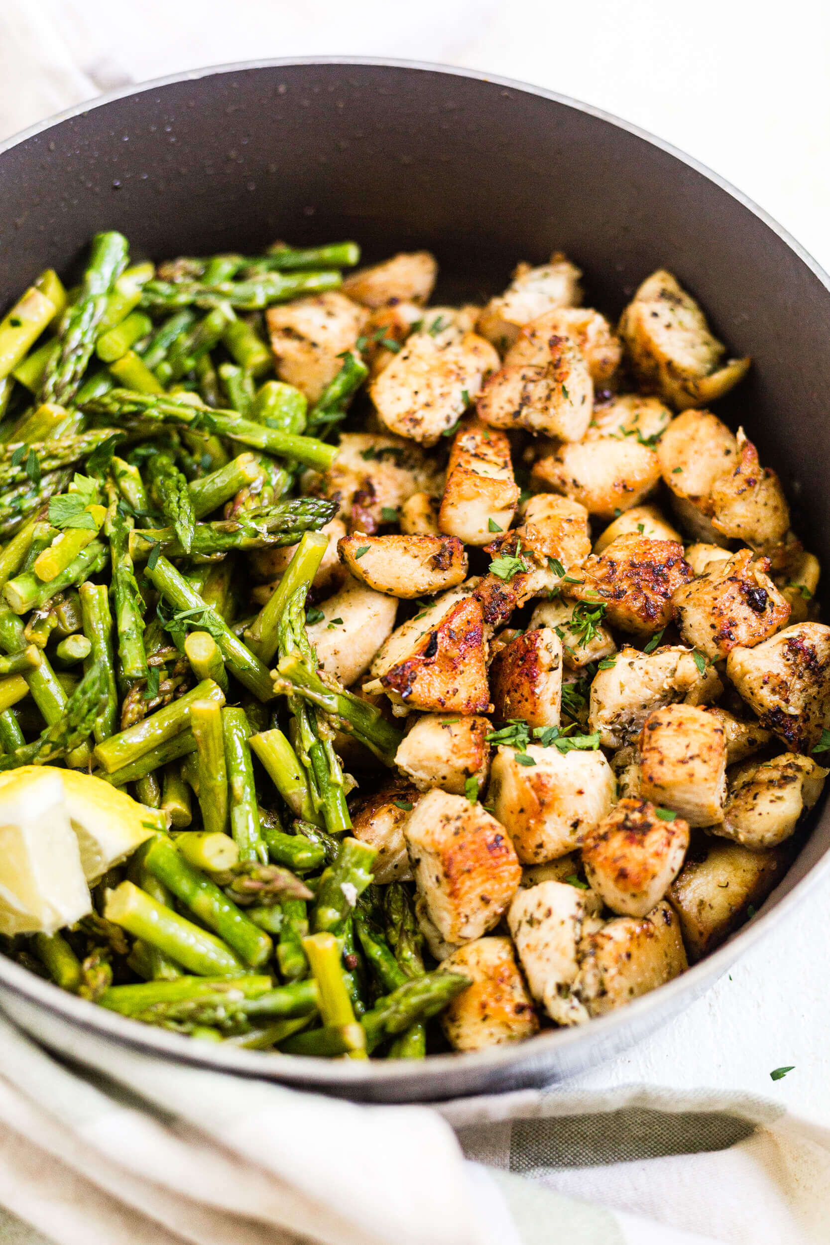 crispy chicken bites in a pan with asparagus