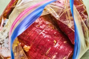 flank steak in pineapple marinade in a plastic bag.