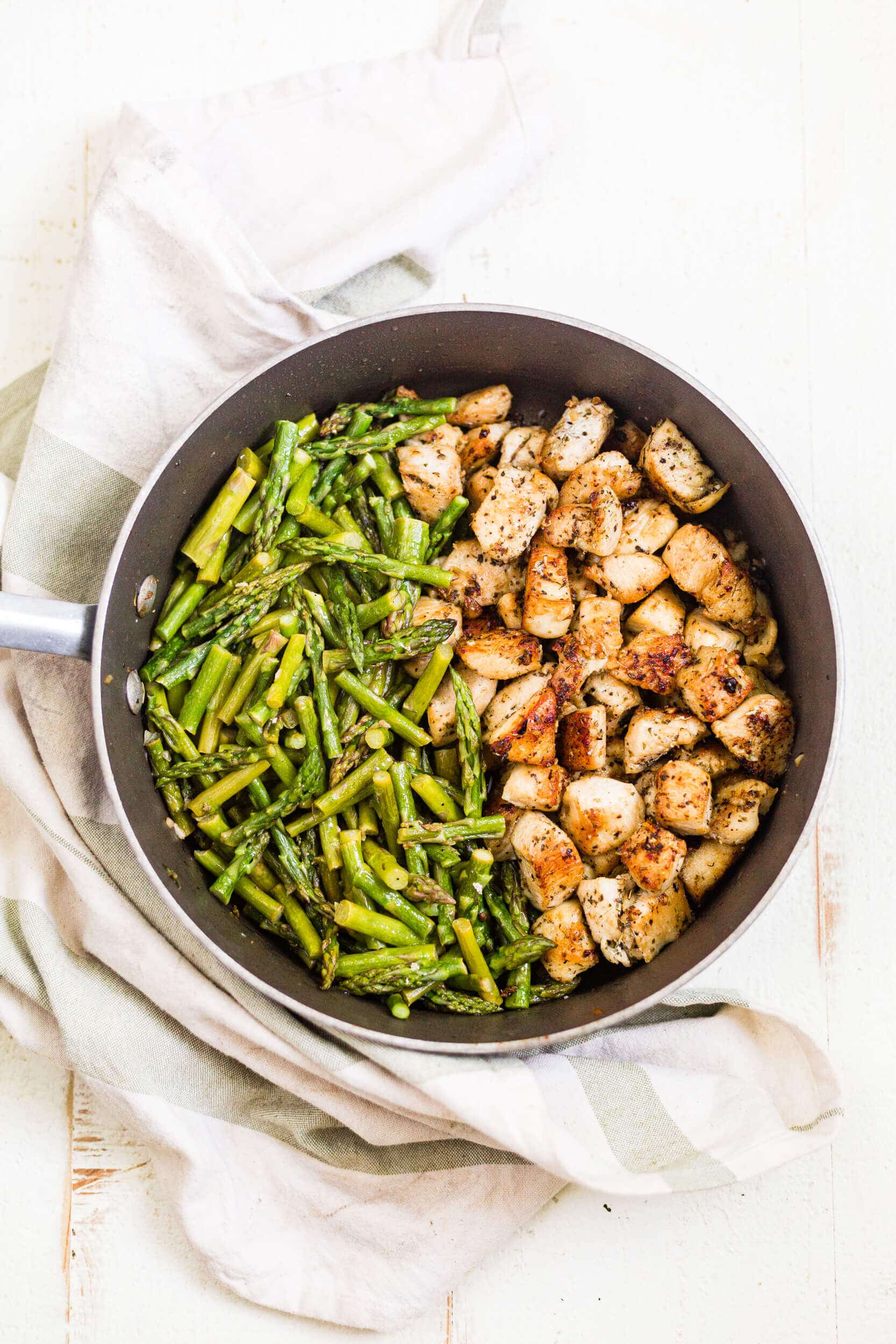 garlic chicken bites with asparagus in a saute pan