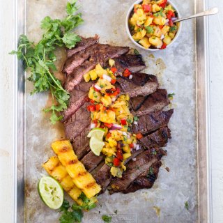 grilled flank steak sliced on a sheet pan with pineapple salsa