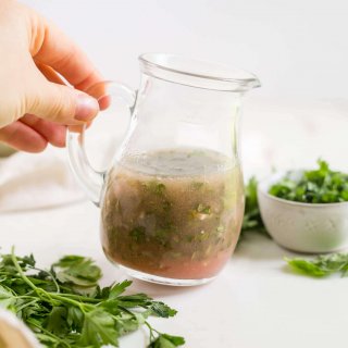 homemade fresh herb vinaigrette in a glass jar with herbs around it