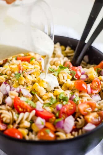 dairy free creamy jalapeno dressing being poure on mexican pasta salad