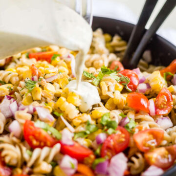 dairy free creamy jalapeno dressing being poure on mexican pasta salad
