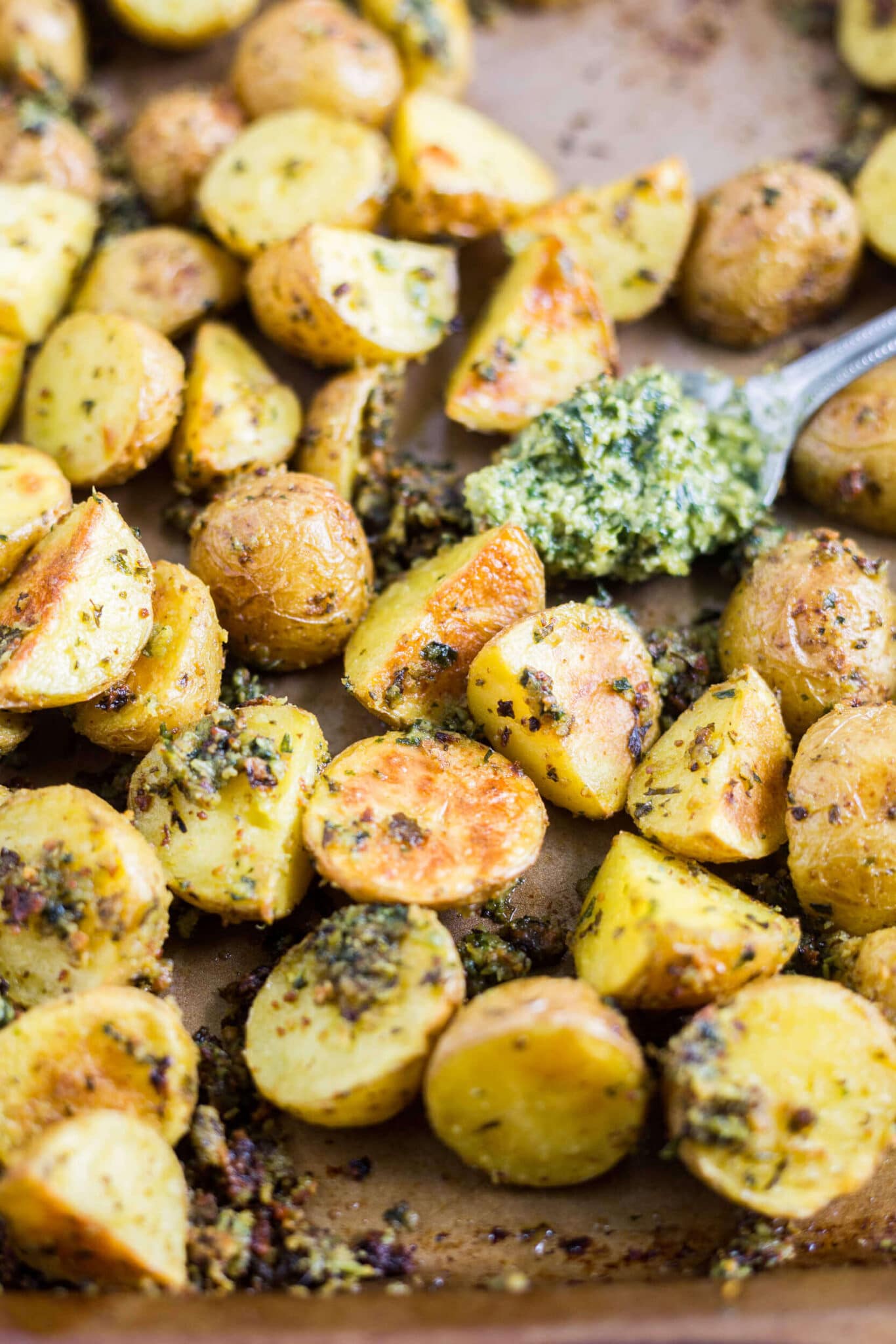 golden crispy potatoes on a sheet pan with pesto