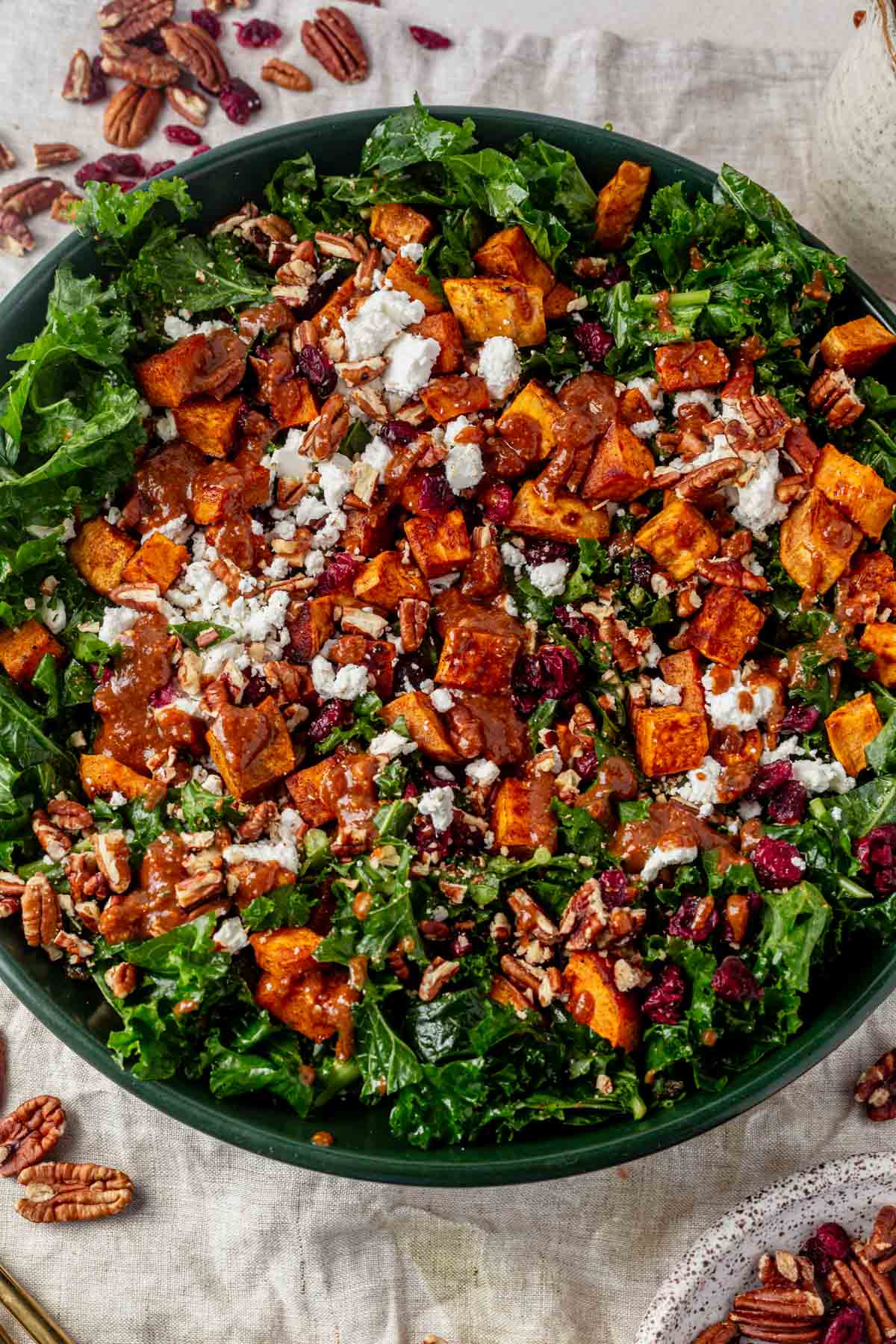 sweet potato kale salad  in a serving bowl with goat cheese and dressing.