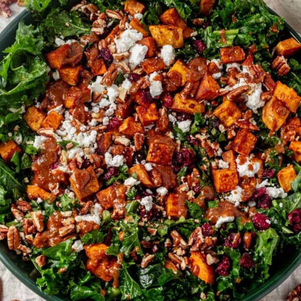 sweet potato kale salad drizzled with dressing in a salad bowl.