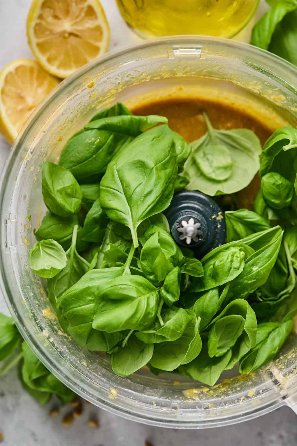 fresh basil and vegan pesto ingredients in a food processor.