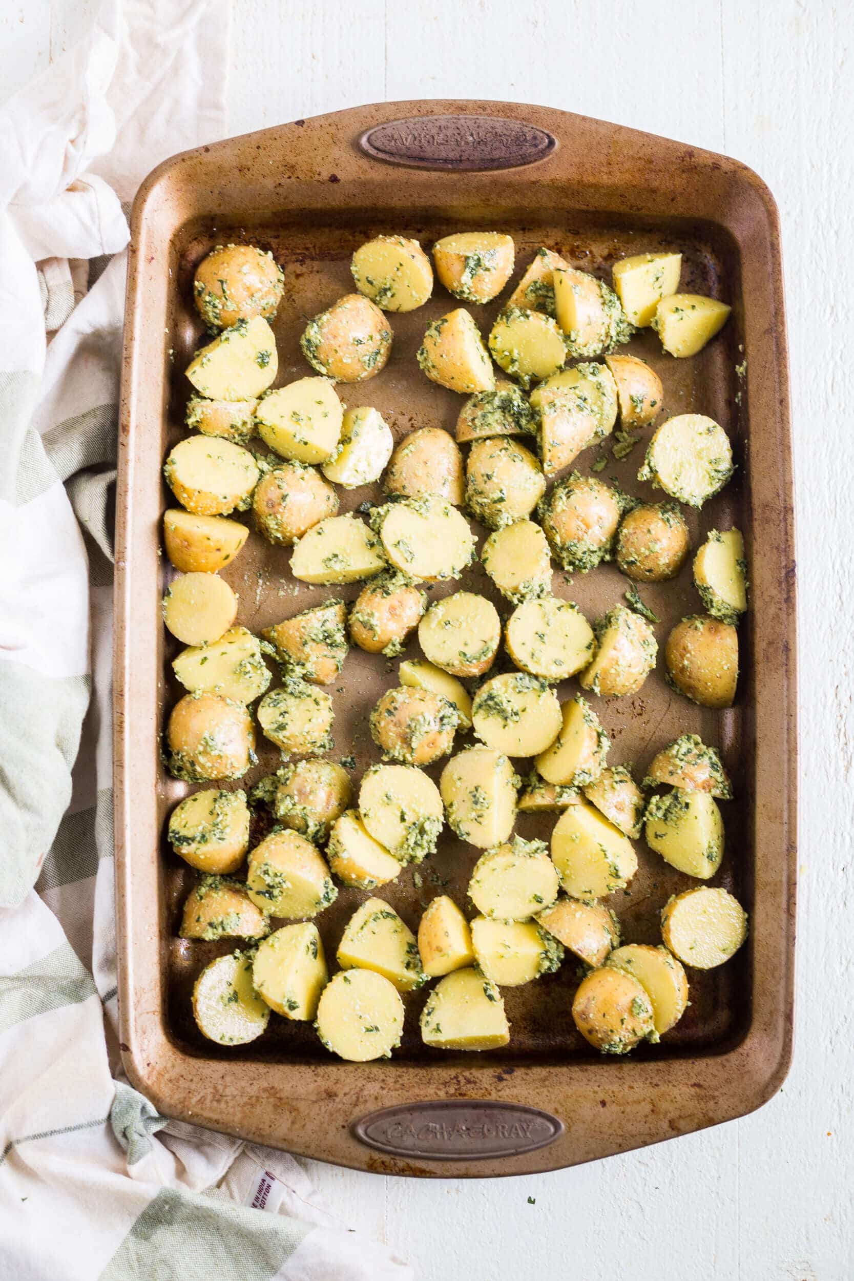 uncooked basil pesto potatoes on a sheet pan before being roasted
