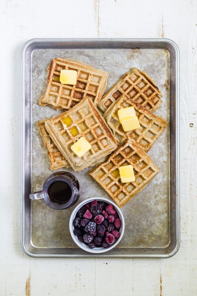6 gluten free waffles on a sheet pan with syrup and berries